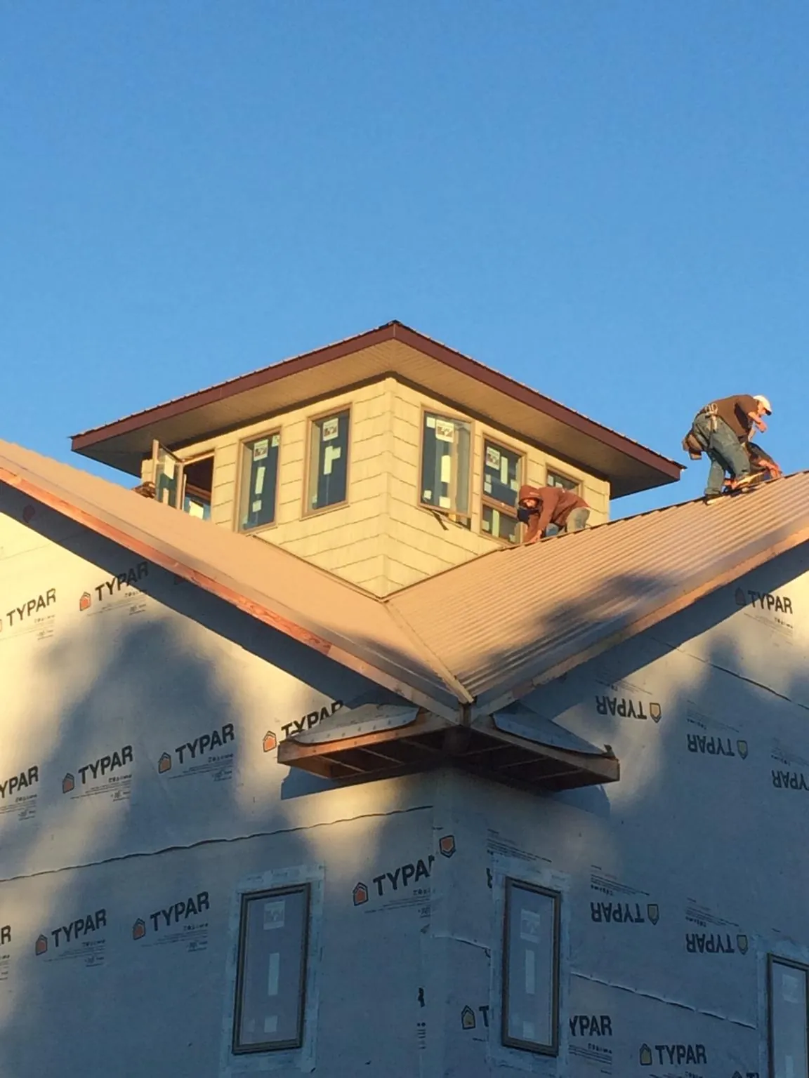 Roofers working around a rooftop cupola on a new metal roof at sunset — Roof Waterproofing in Auburndale by Roofing Brothers